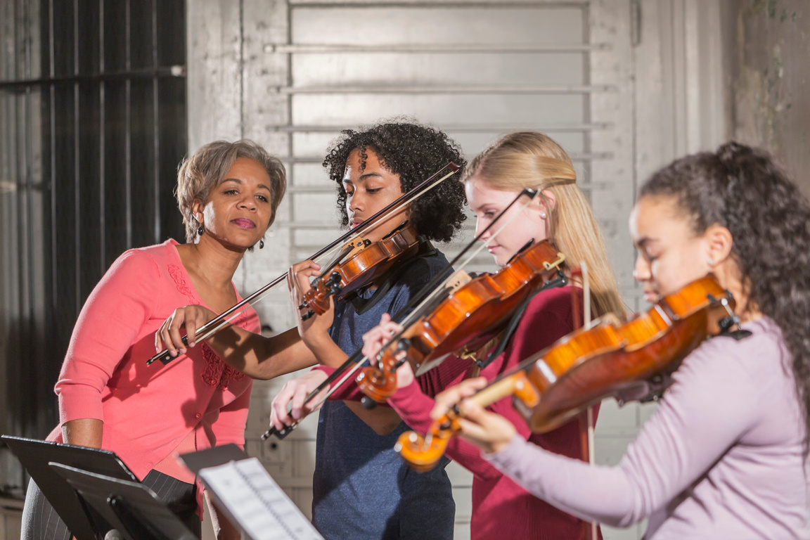Teenage violinists with music teacher