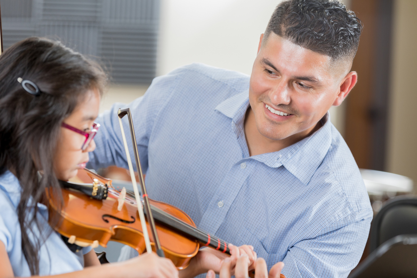 Cheerful music teacher helps student with violin lessons